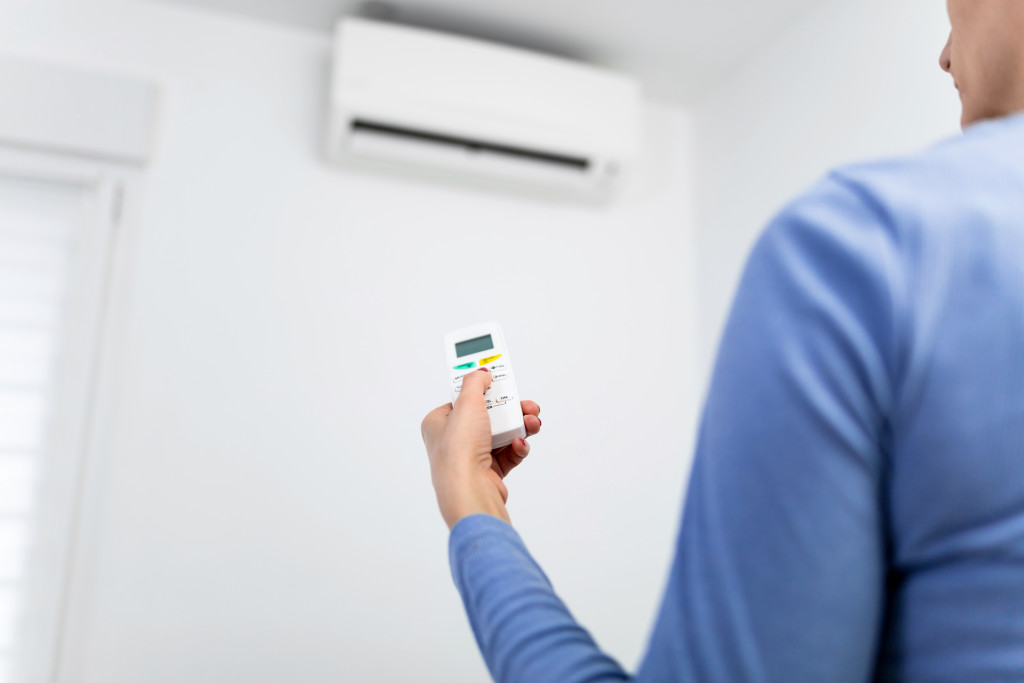 A woman changing the temperature of an air conditioner at home